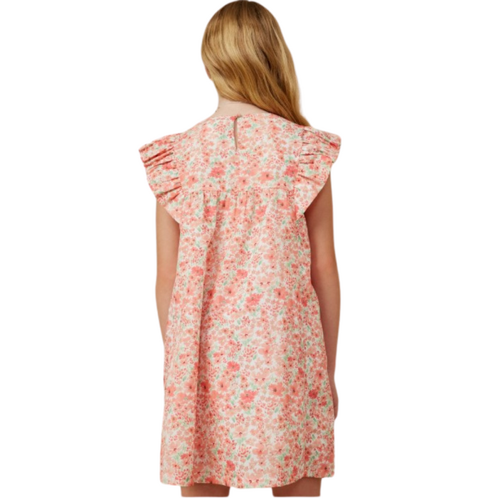 Girl wearing coral ditsy floral dress with ruffle sleeves and back keyhole button closure, hair down.