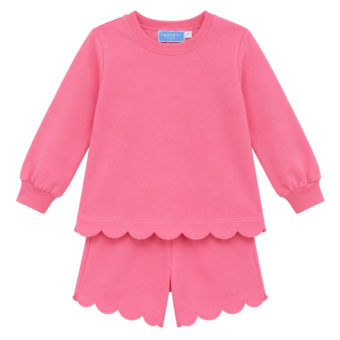Girls pink two-piece set with long sleeve top and scalloped hem shorts, featuring soft fabric and a relaxed fit.