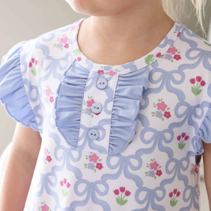 Child wearing a nightgown with floral and bow patterns showing the three button accent closeup