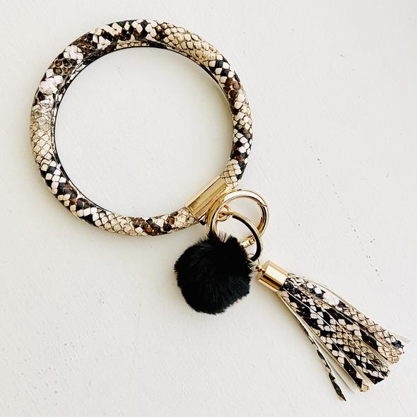 black and cream snake skin bangle with a black pom pom and a cream and black snake skin fringe