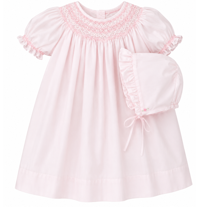 Pink smocked baby dress with ruffled sleeves on a white background