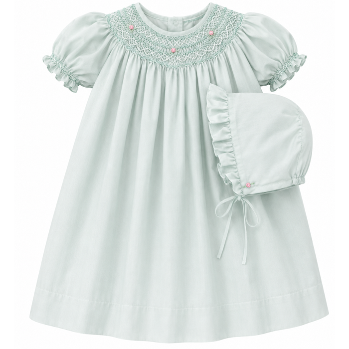 Light min baby dress with smocked details on a white background