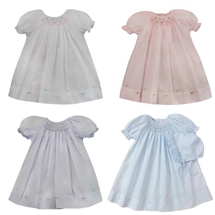 Four baby dresses in different colors on a white background