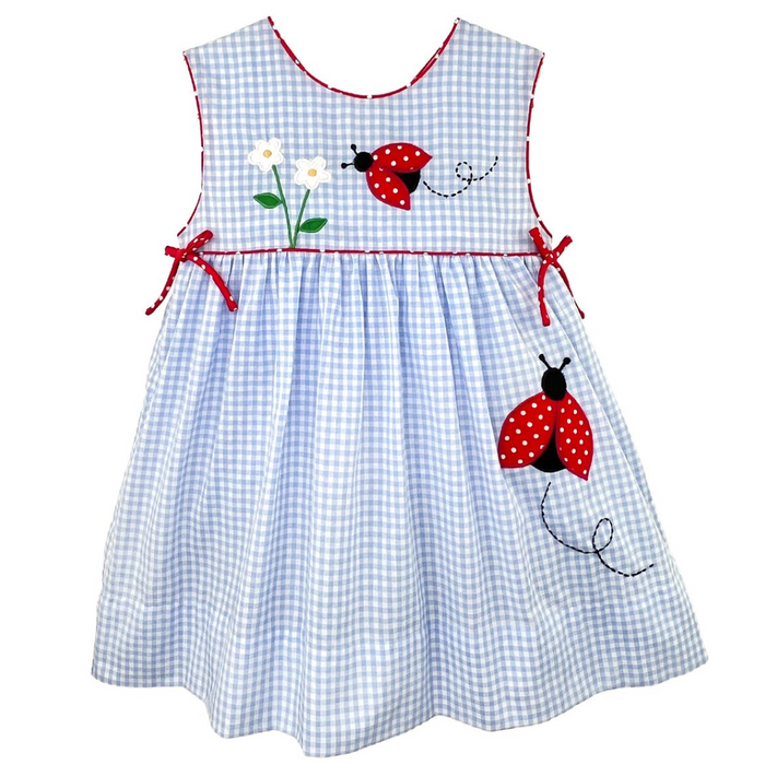 sleeveless blue gingham dress trimmed  and piped in red with red side bows and a flower and lady bug appilque