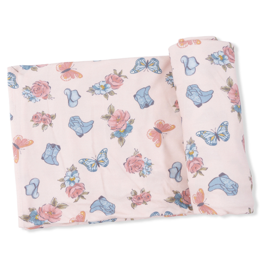 pink swaddling blanket with a butterfly, floral and cowgirl hat and boot print