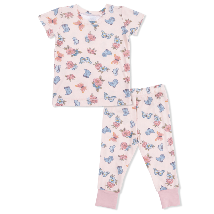 Children's pajama set with floral and cowgirl boot pattern on a light pink background
