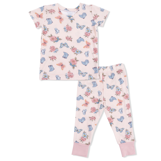 Children's pajama set with floral and cowgirl boot pattern on a light pink background