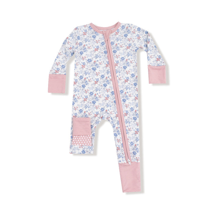 Baby romper with vintage floral print in blue and rose, pink trim, two-way zipper, and polka dot knee and footie accents.