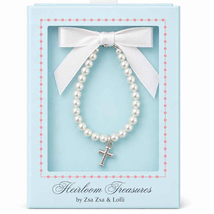 crystal pearl baby bracelet  with a silver cross accent  in a decorative box labeled 'Heirloom Treasures by Zsa Zsa & Lolli'.