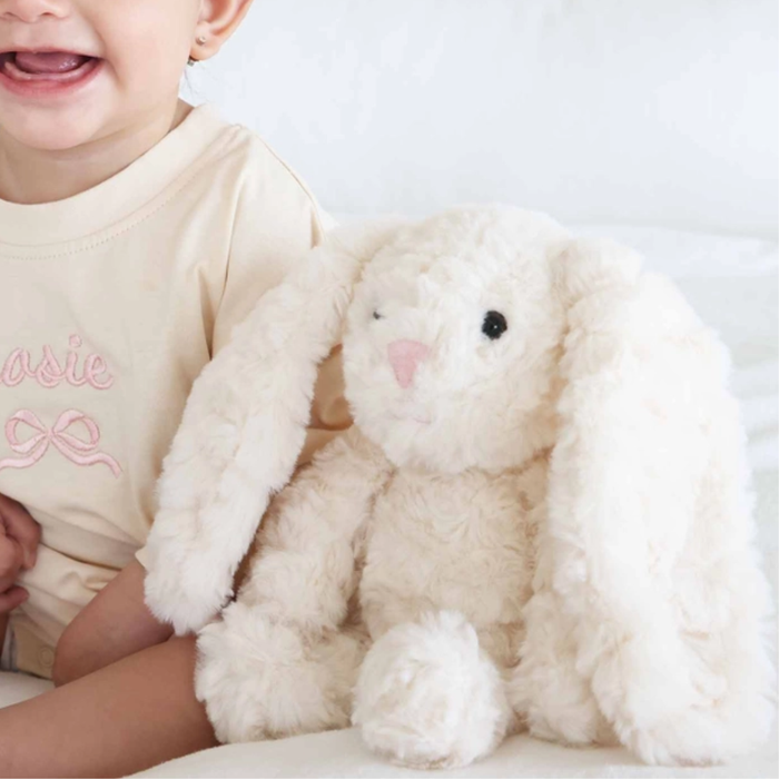 Child holding a plush bunny toy with a plain background