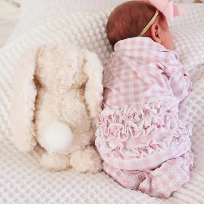 the backside of a plush bunny with cottontail next to a sleeping baby