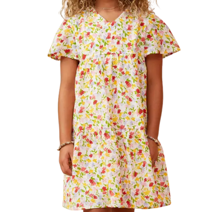 Tween girl wearing a colorful ditsy floral dress with flutter sleeves, V-neck, and tiered skirt.