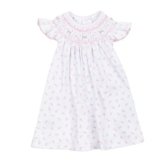 White baby bishop dress with pink floral print, hand-smocked neckline, flutter sleeves, and flowing silhouette on a white background