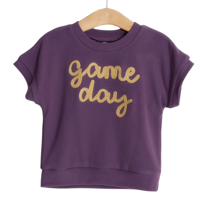 Girls purple short sleeve top with gold “game day” script lettering on hanger
