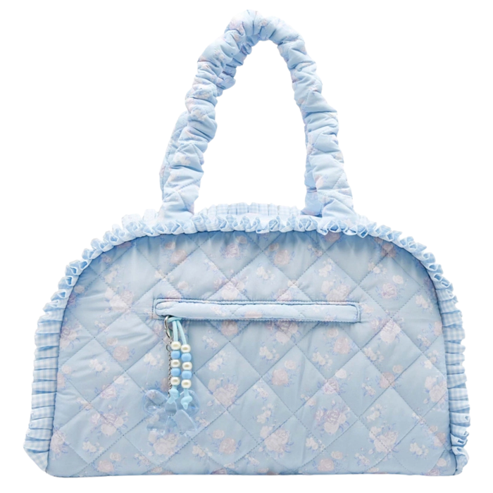 Light blue quilted floral duffle bag with ruffle trim, padded handles, and decorative zipper charm