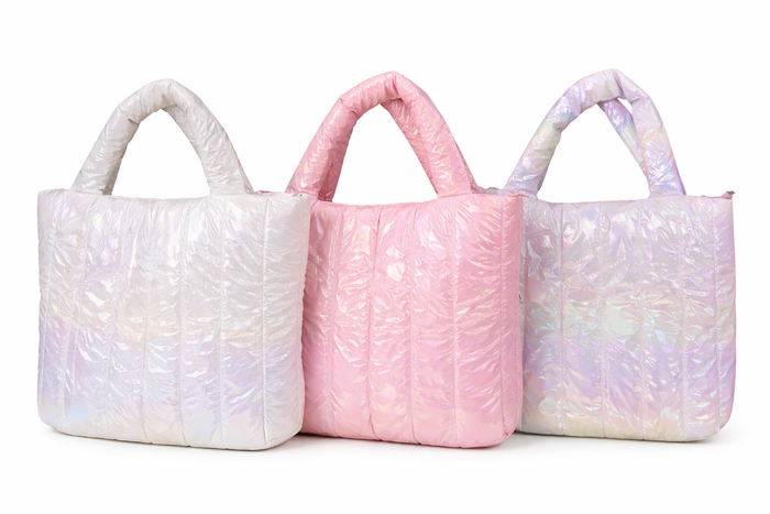 Iridescent quilted tote bags in white, pink, and pastel rainbow finishes with padded handles, displayed side by side on a white background
