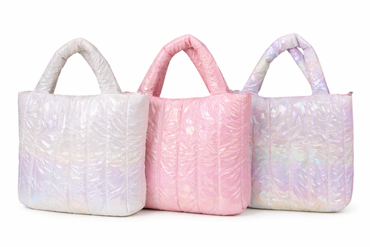 Iridescent quilted tote bags in white, pink, and pastel rainbow finishes with padded handles, displayed side by side on a white background