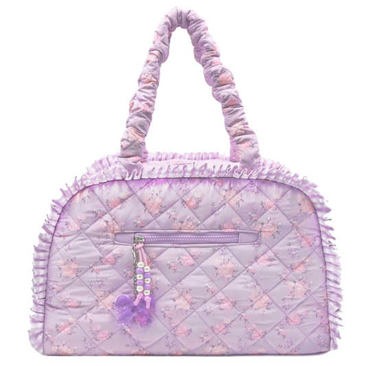 Purple quilted floral duffle bag with ruffle trim, padded handles, and decorative zipper charm