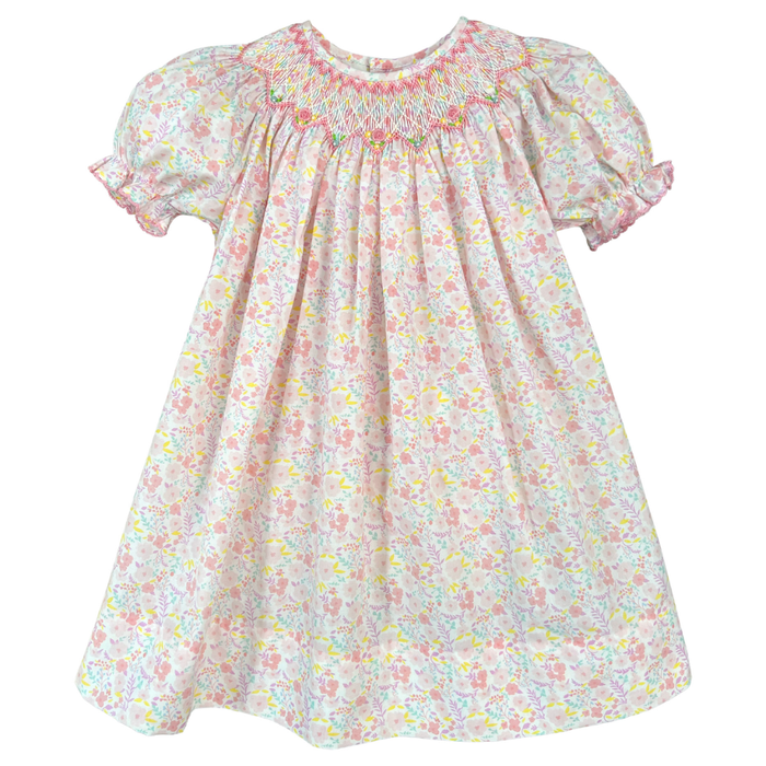 Girls pastel floral smocked dress with hand-embroidered yoke, puff sleeves, and flowing skirt on white background.
