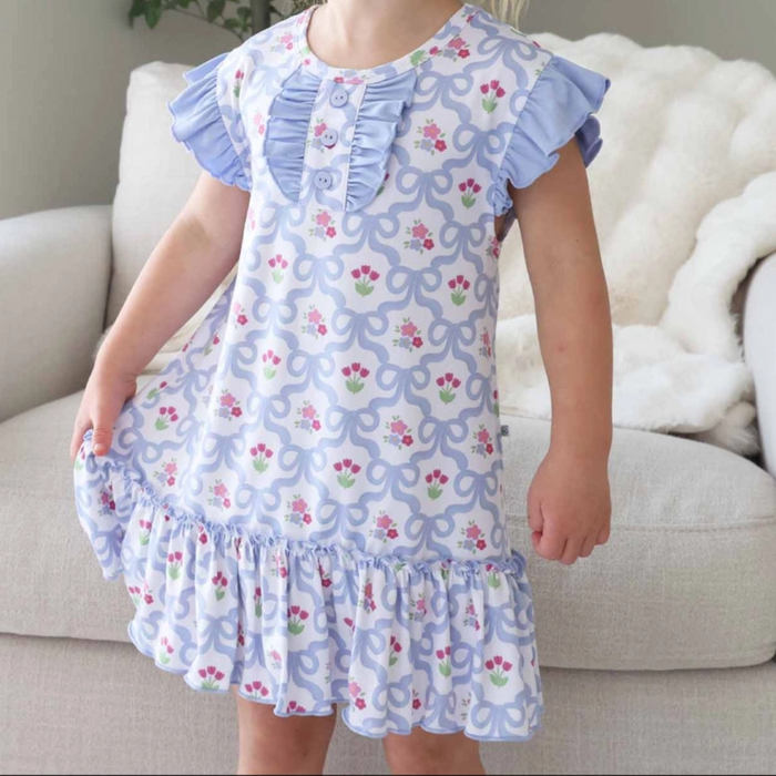 Child wearing a floral night gown with ruffled details in a living room setting